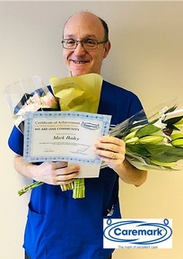 Mark Bailey in his Caremark uniform with flowers and certificate. Credit: Caremark