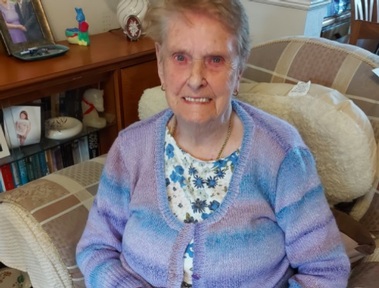 Redditch home care client Florrie wears the new cardigan she finished knitting with her live-in carer. Credit: Home Instead